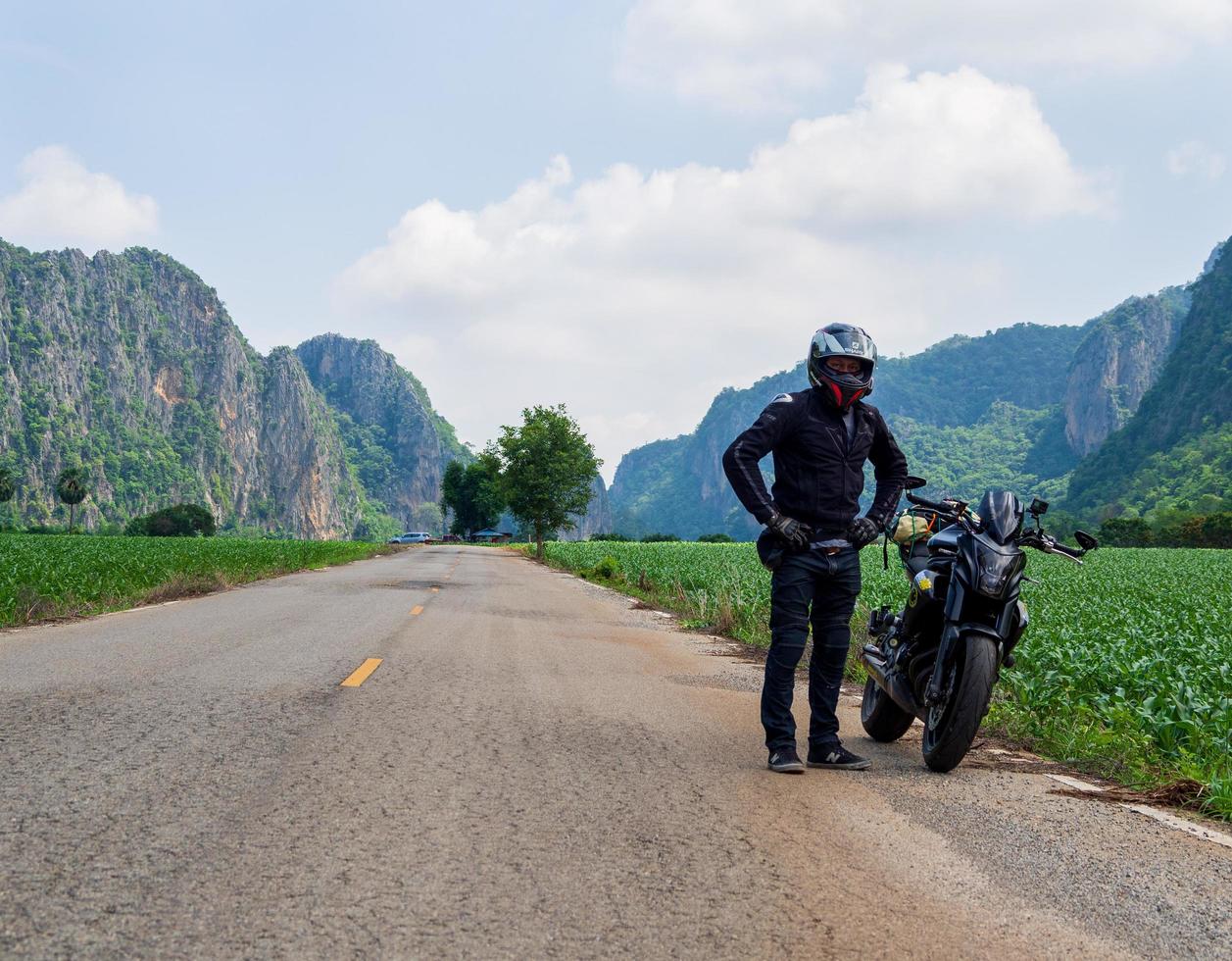 front view of trave alone road mountain sky, helmet, wearing black protective clothing Take a black adventure motorcycle Kawasaki ER6n journry to various places. photo