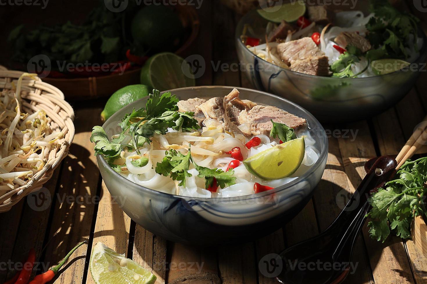 Vietnamese Noodle Soup Pho Bo with Beef on a Bamboo Table photo