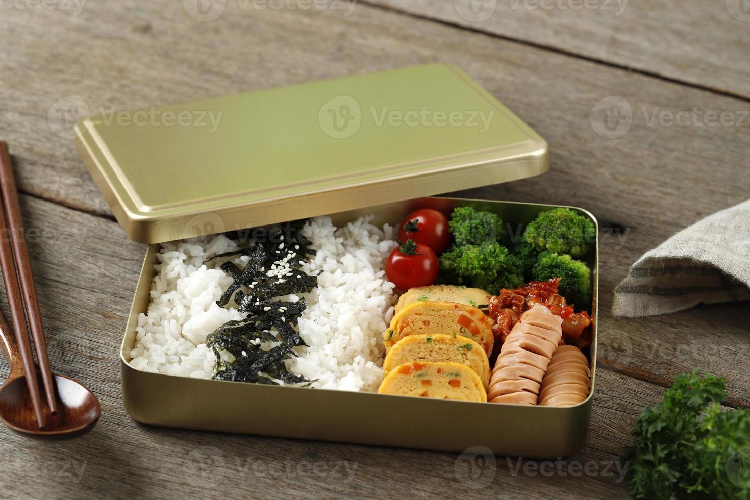 Dosirak Korean Lunch Box Contain Steamed Rice with Gyeranmari, Sausage, Kimchi, Tomato, and Steamed Broccoli photo