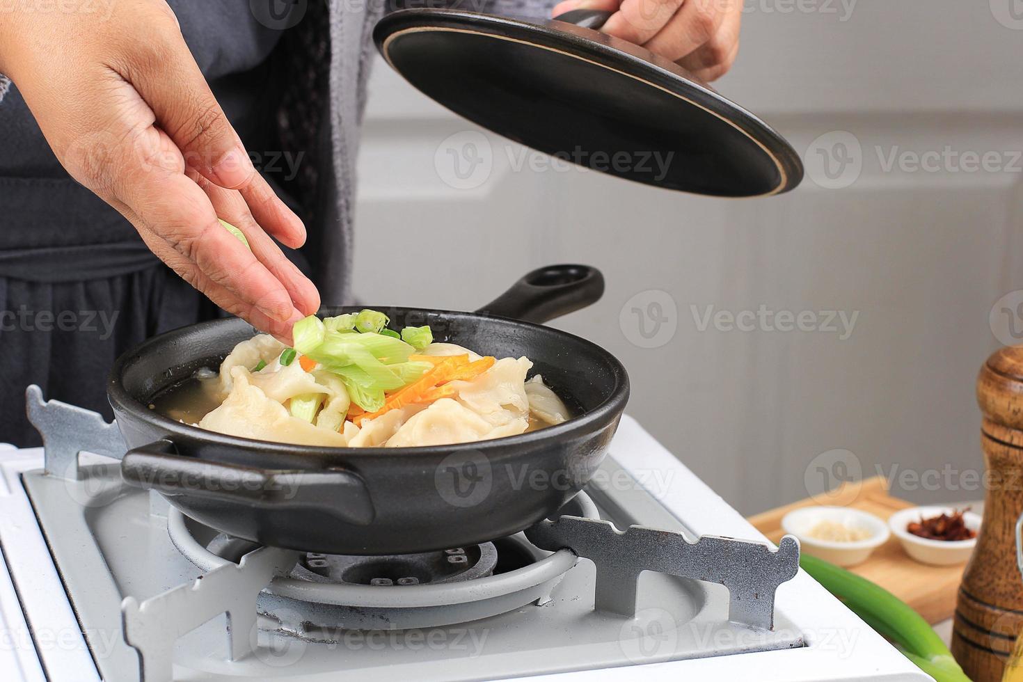 Cooking Dim Sum Soup Mandu Guk, Korean Dumpling Soup with Spring Onion Topping photo