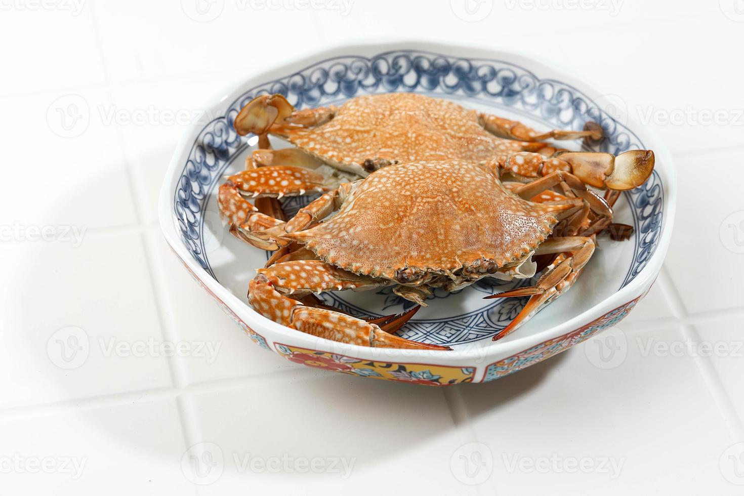 cangrejo azul al vapor servido en un plato de cerámica chino sobre fondo blanco, preparación de alimentos. foto