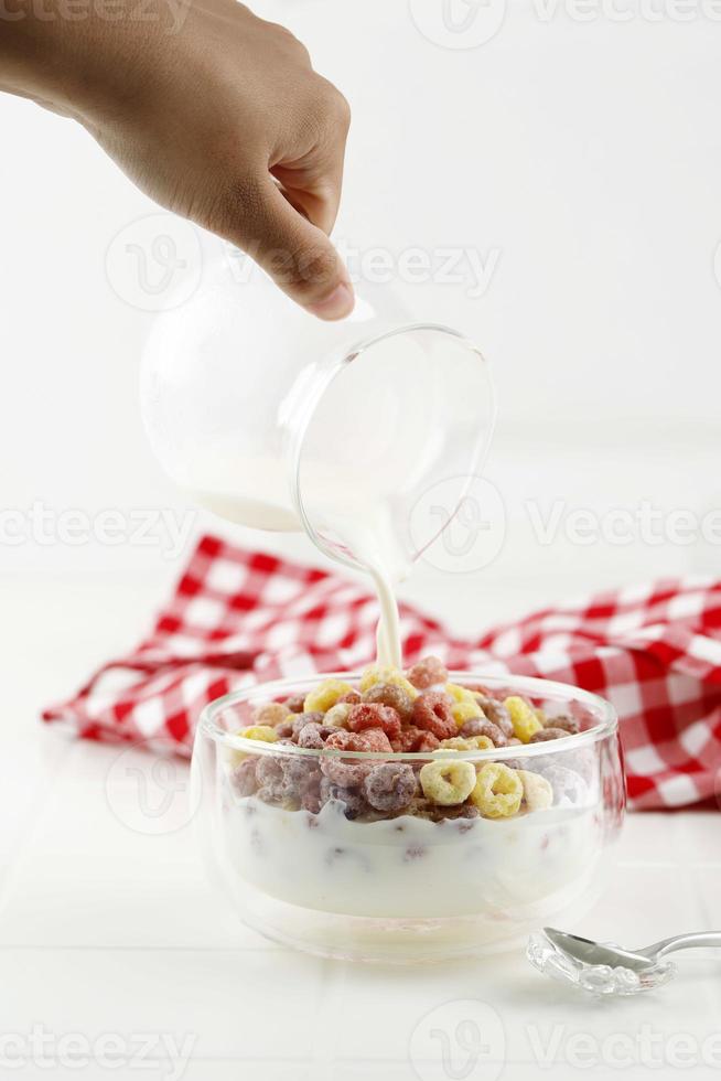 vierta la leche en el tazón con un colorido anillo de cereal foto