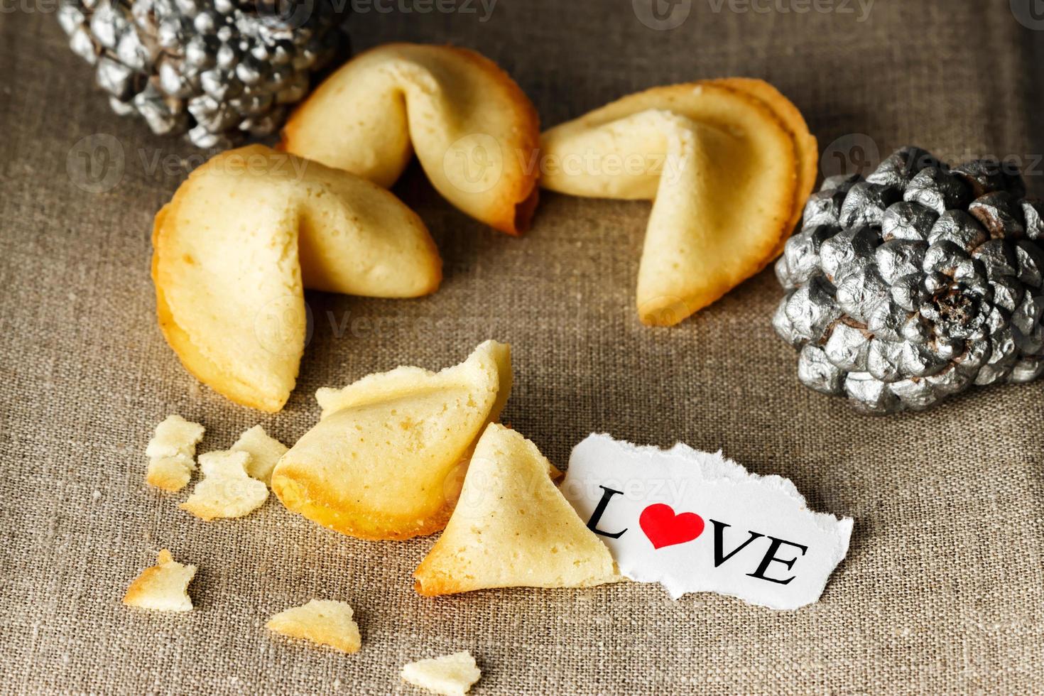 galletas con forma de tortellini con la palabra amor escrita en un papel y dos piñas plateadas en el fondo.imagen horizontal. foto