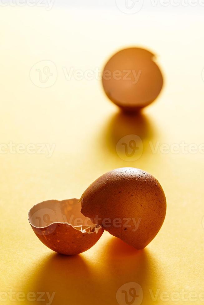 Egg shells on yellow surface with more shells in the background. View in the foreground. Food for a healthy life. Vertical image. photo