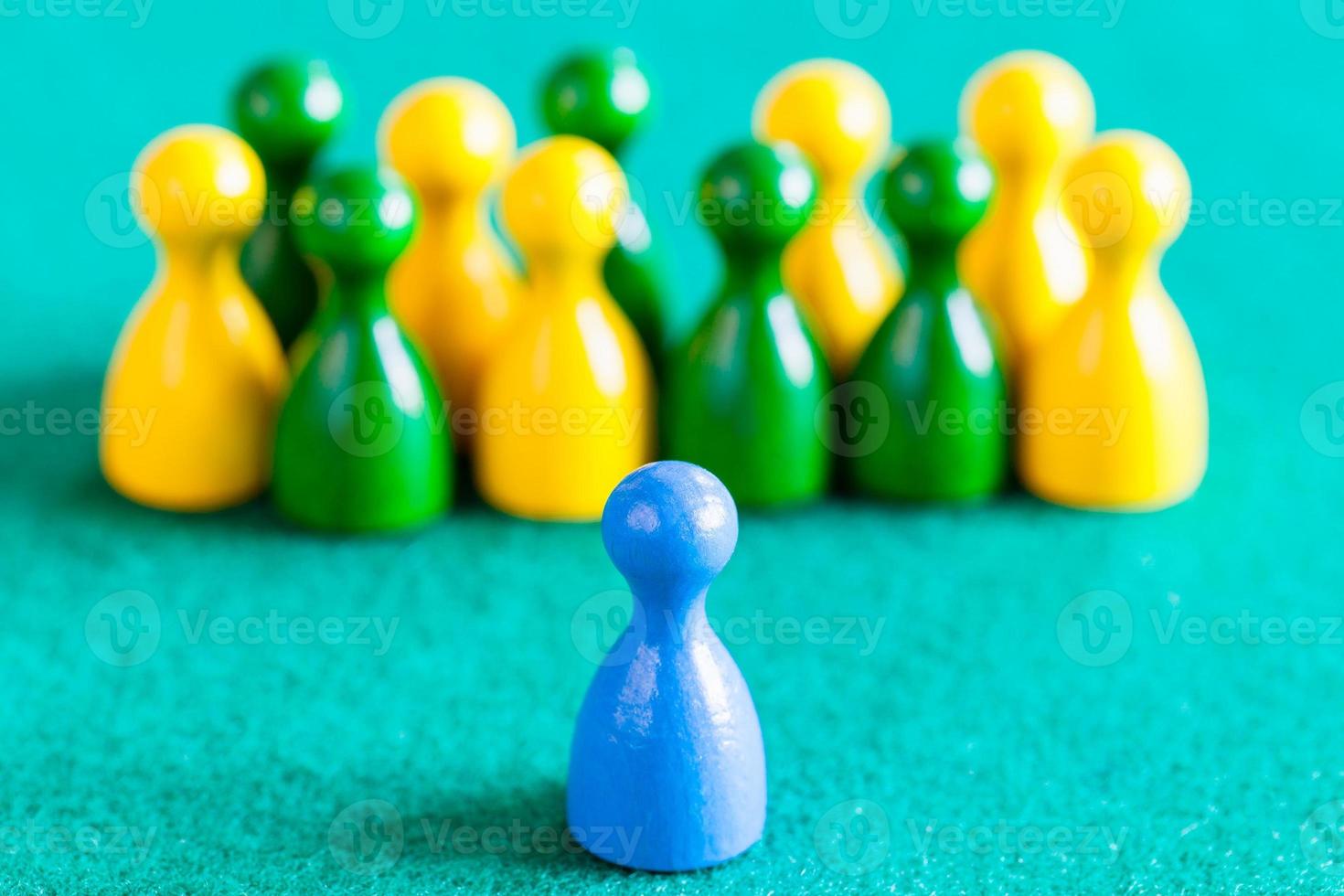 one blue pawn in front of other color pawns photo