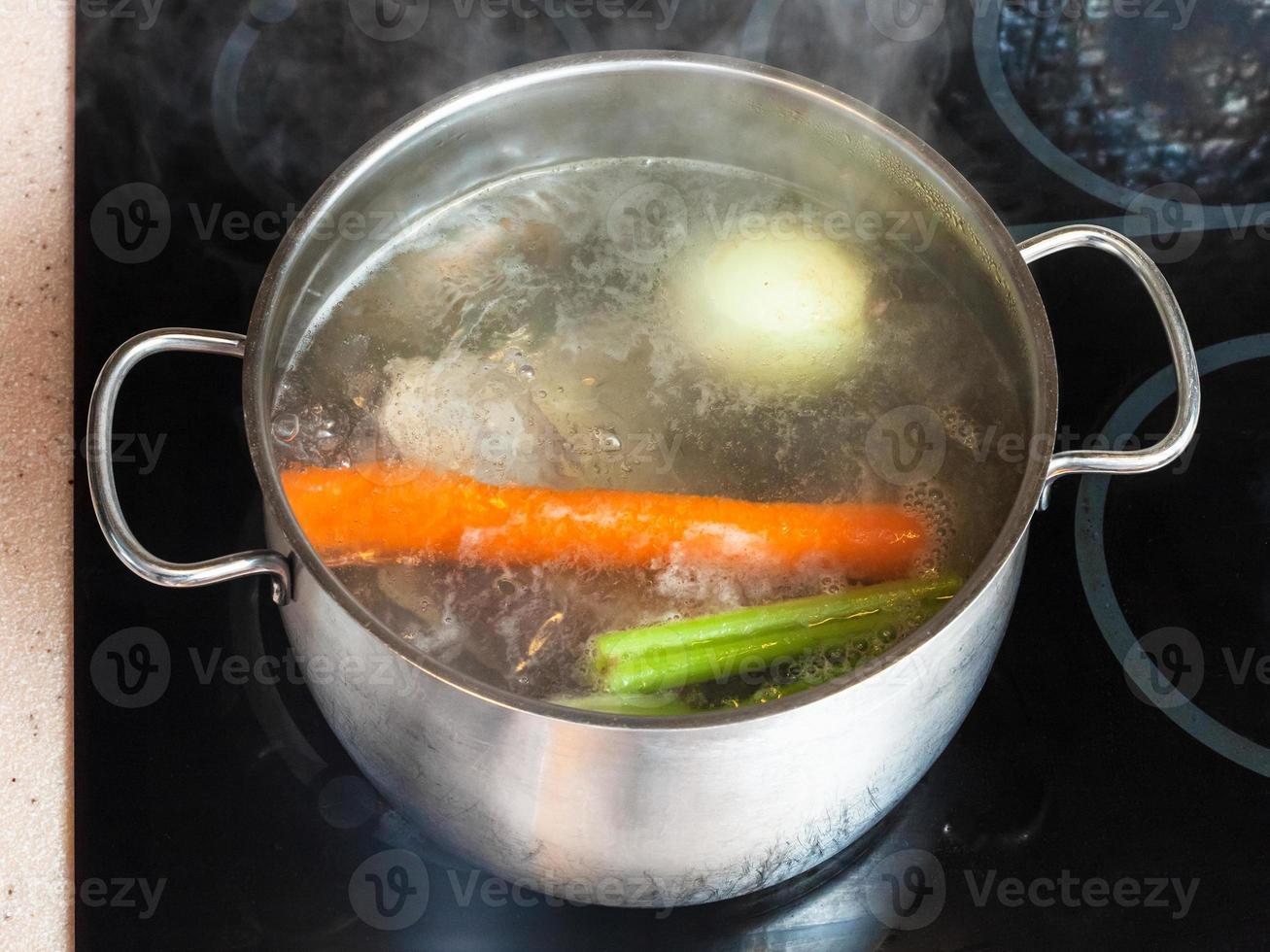 boiling meat stock in stockpot on ceramic cooker photo