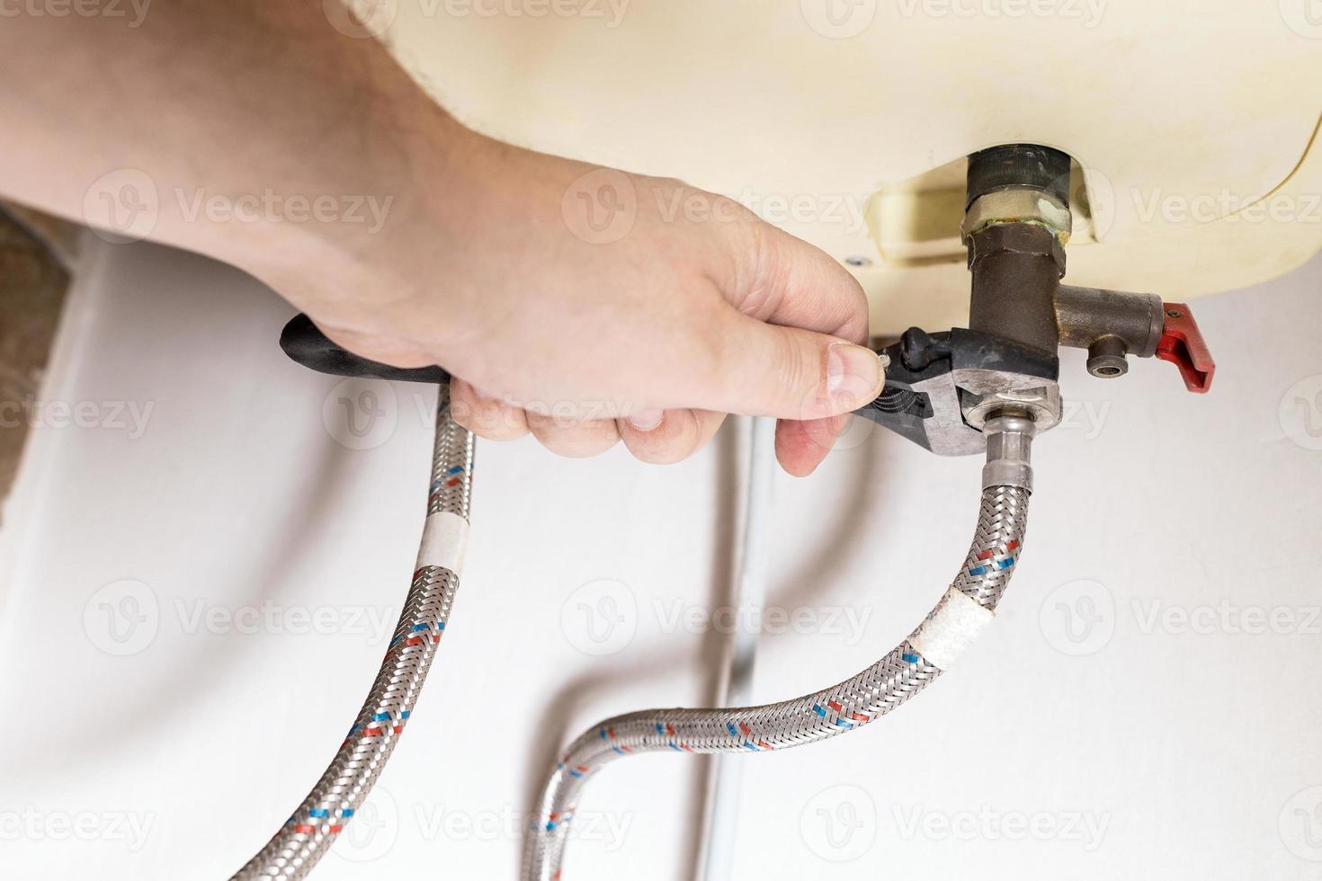 La mano instala la válvula con una llave ajustable en la caldera foto