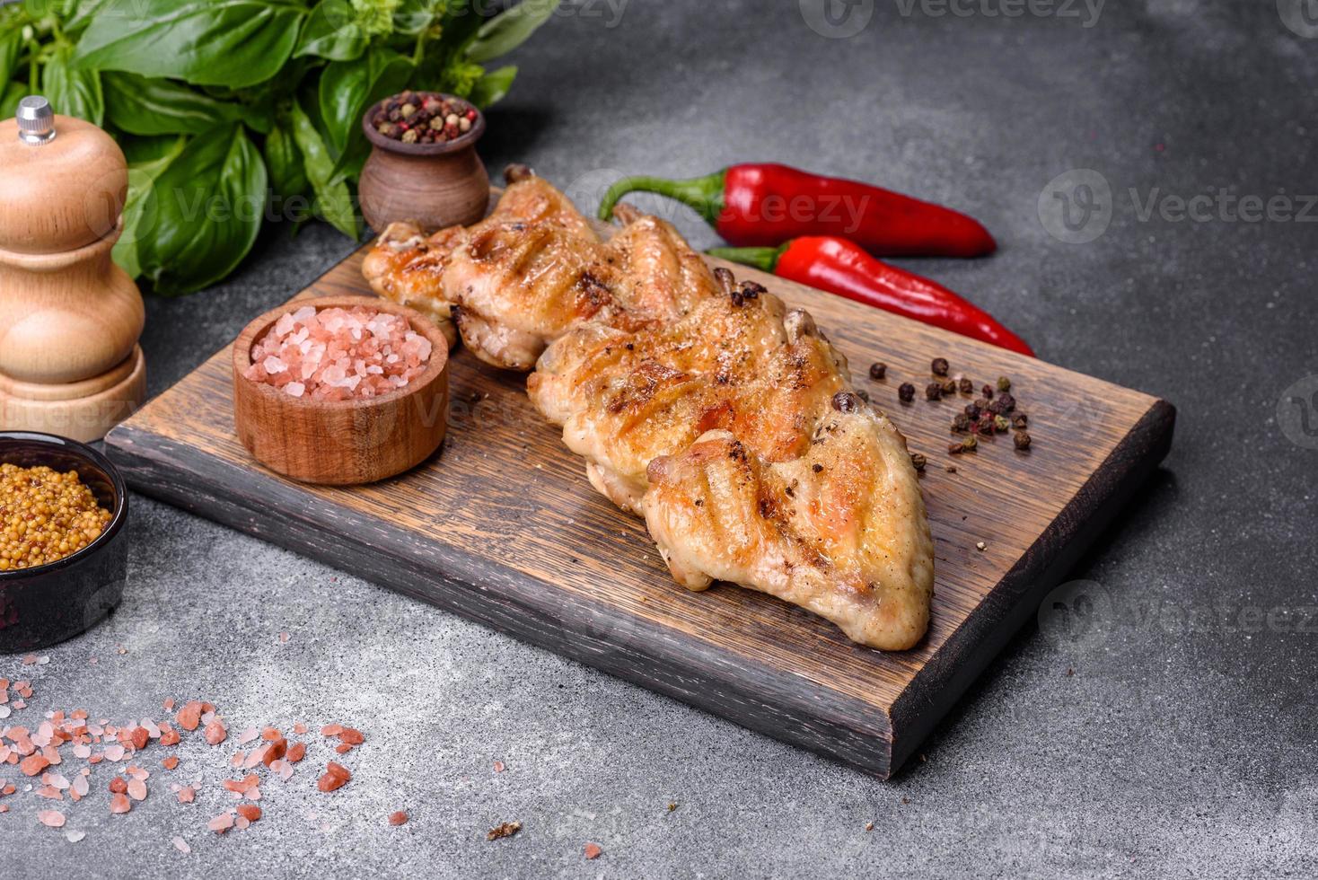 alitas de pollo al horno con semillas de sésamo y salsa en una tabla de cortar de madera foto