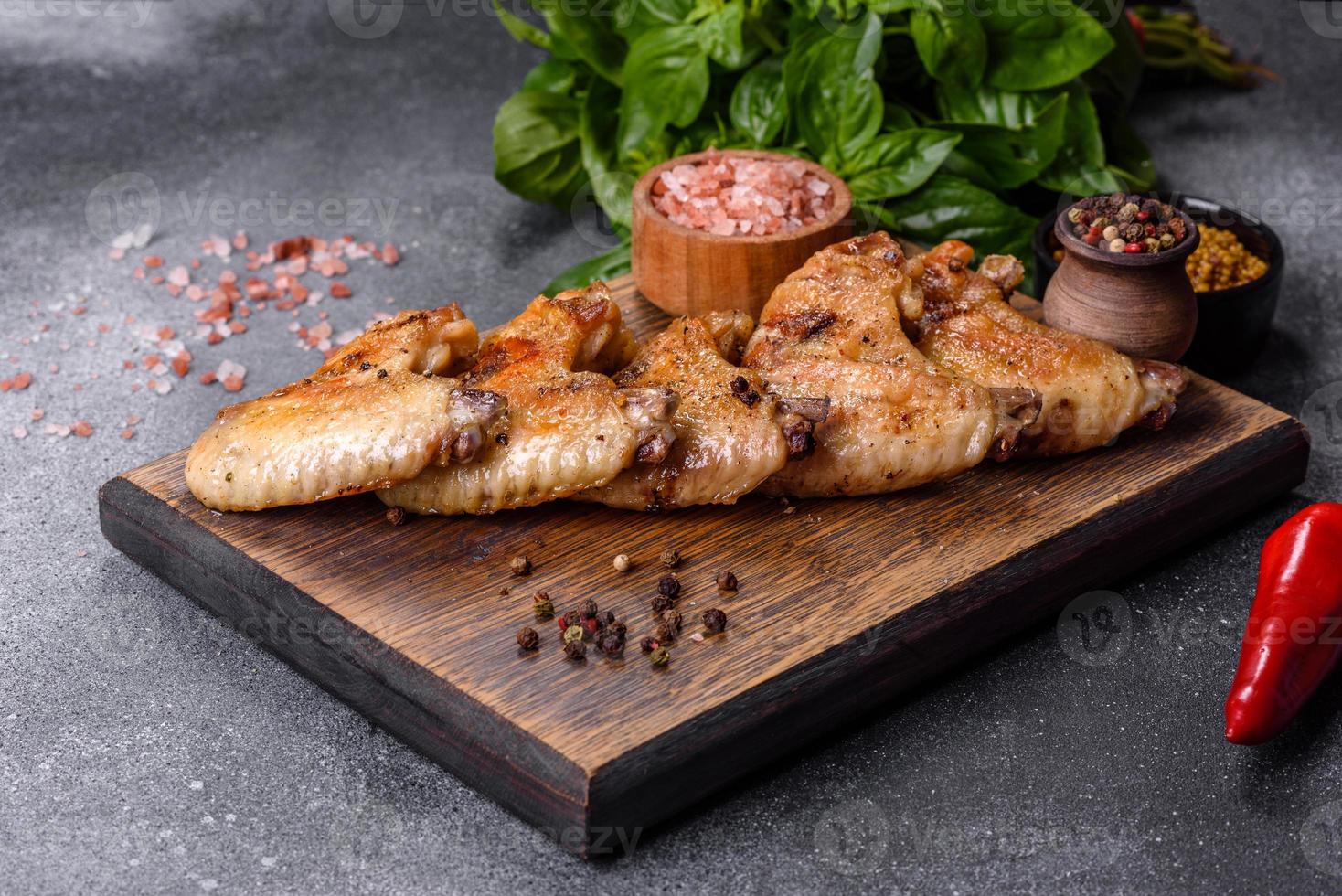 Baked chicken wings with sesame seeds and sauce on a wooden cutting board photo