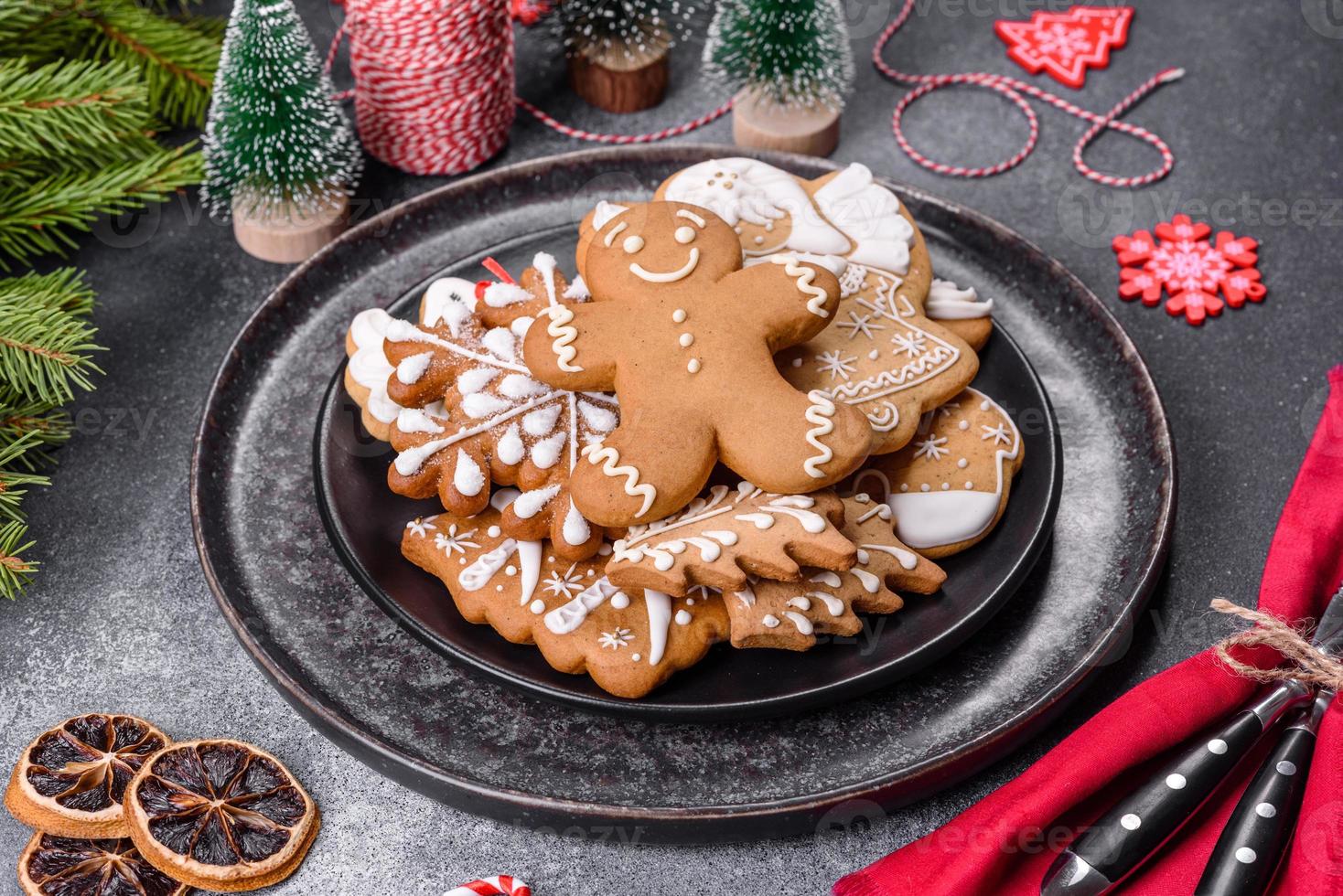 pan de jengibre, adornos de árboles de Navidad, cítricos secos sobre un fondo de hormigón gris foto