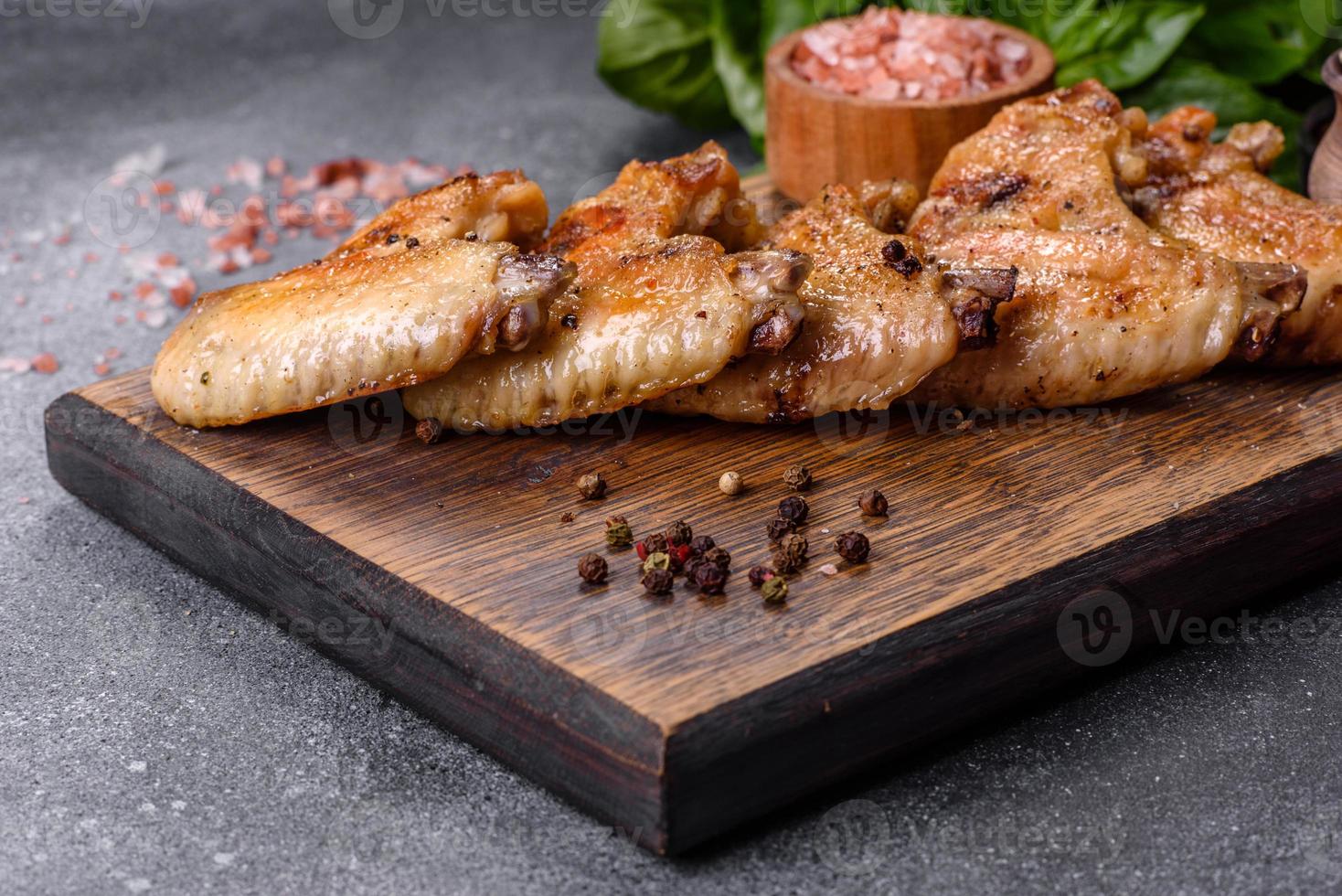 Baked chicken wings with sesame seeds and sauce on a wooden cutting board photo