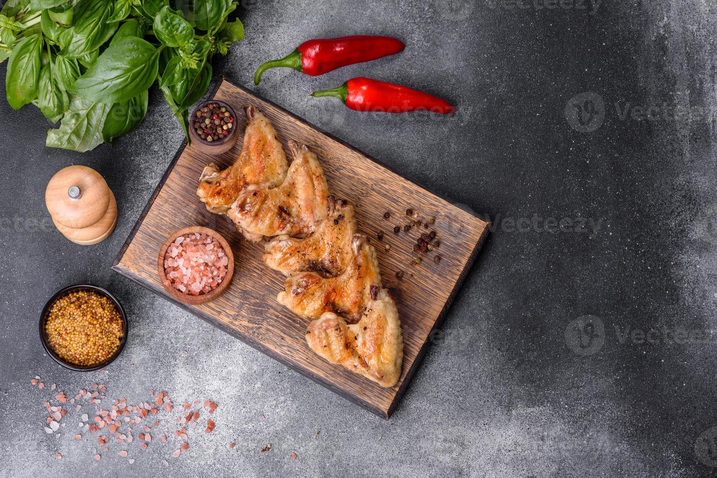 Baked chicken wings with sesame seeds and sauce on a wooden cutting board photo