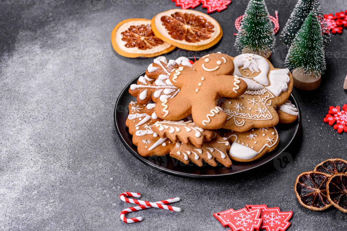 pan de jengibre, adornos de árboles de Navidad, cítricos secos sobre un fondo de hormigón gris foto