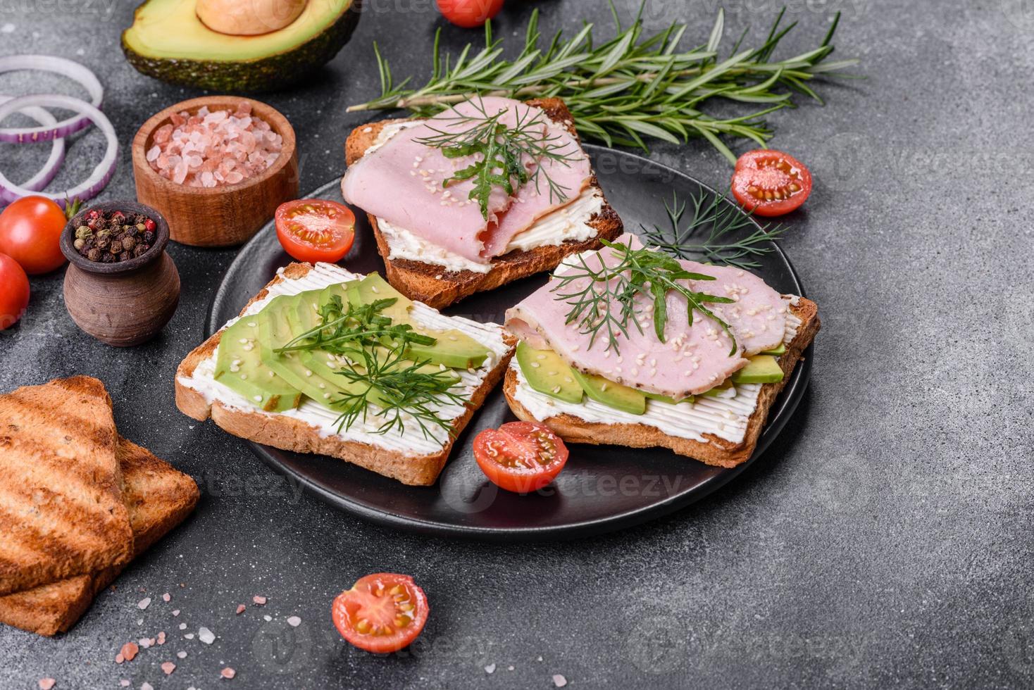 Fresh, delicious ham, butter, avocado and sesame seeds sandwiches on a wooden cutting board photo