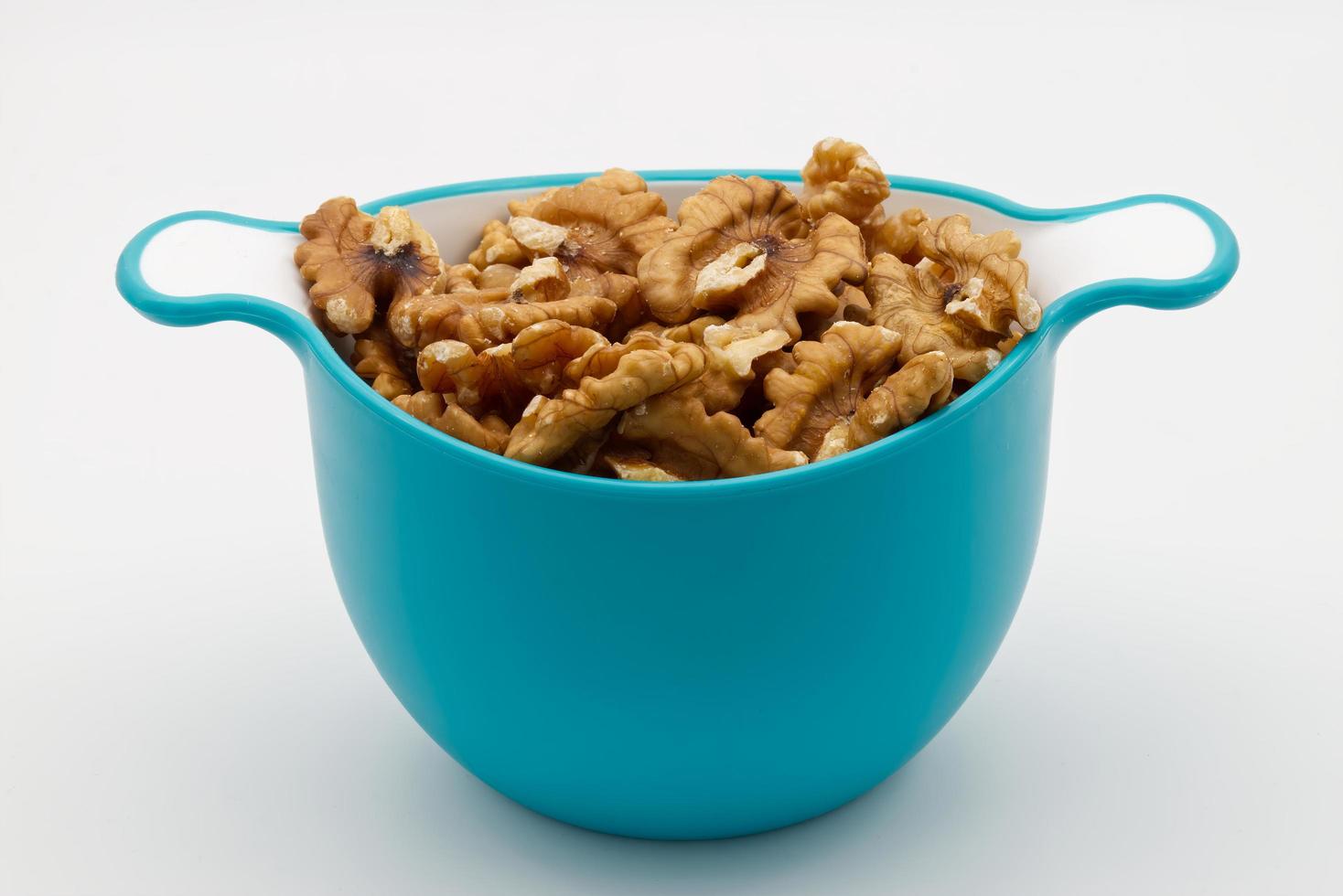 Pile of walnuts in a plastic blue bowl isolated on white background. photo