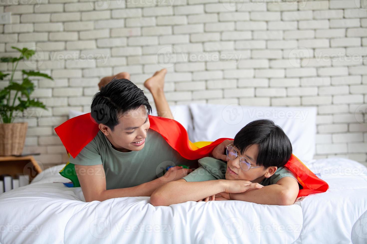 Happy asian gay couple talking together and relaxing at home on bed, LGBTQ concept. photo