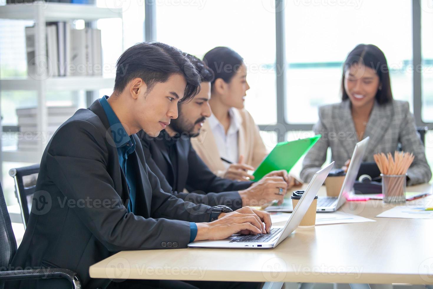 los colegas masculinos y femeninos del equipo de negocios asiático que hablan en el trabajo comparten ideas con una computadora portátil, los colegas felices trabajan juntos en la computadora en la oficina. foto