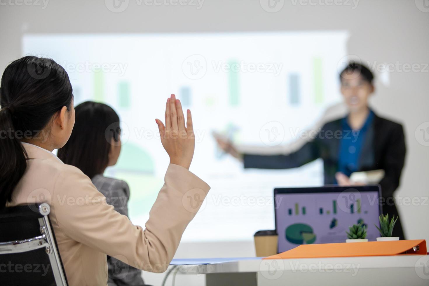 Asian business team male and female colleagues talking at work share ideas with chart on board, colleagues raised hands for question. photo