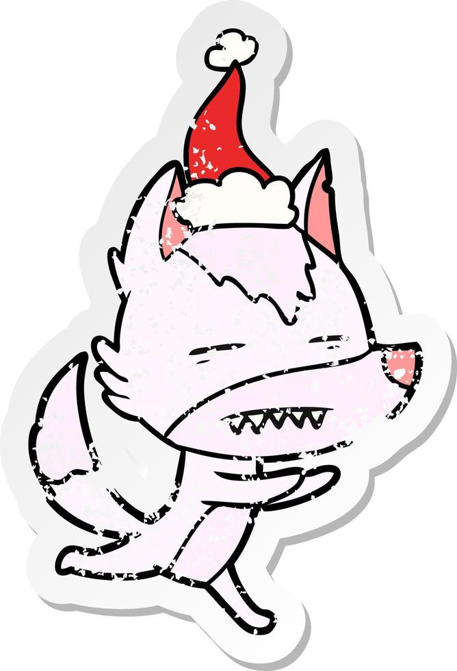 distressed sticker cartoon of a wolf showing teeth wearing santa hat vector