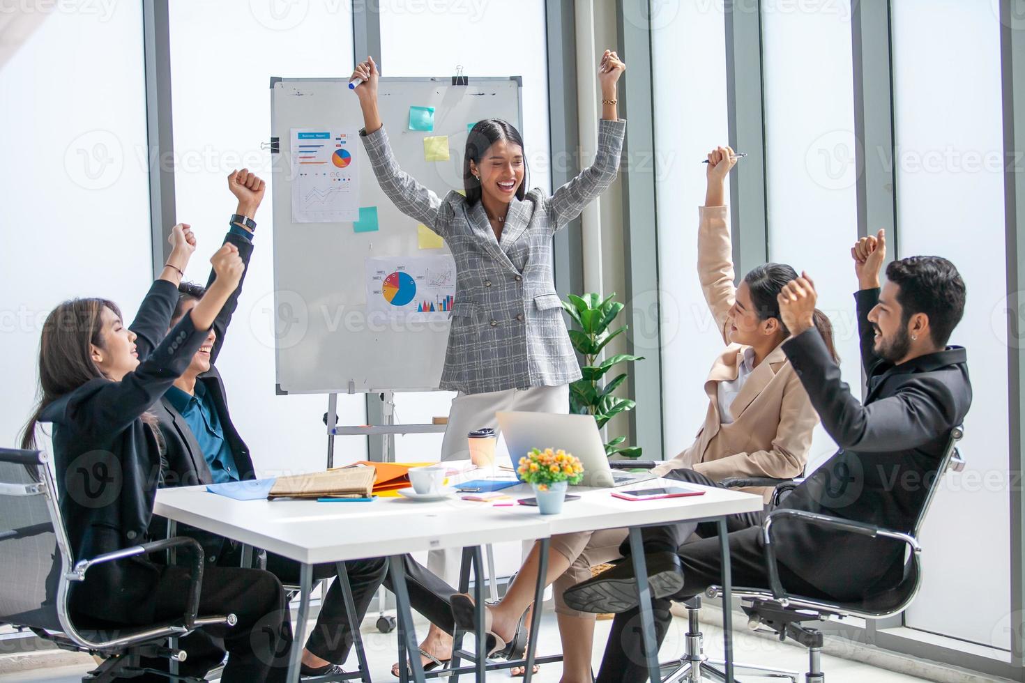 Asian business team celebrate corporate victory together in office, laughing and rejoicing, smiling excited employees colleagues screaming with joy in office. photo