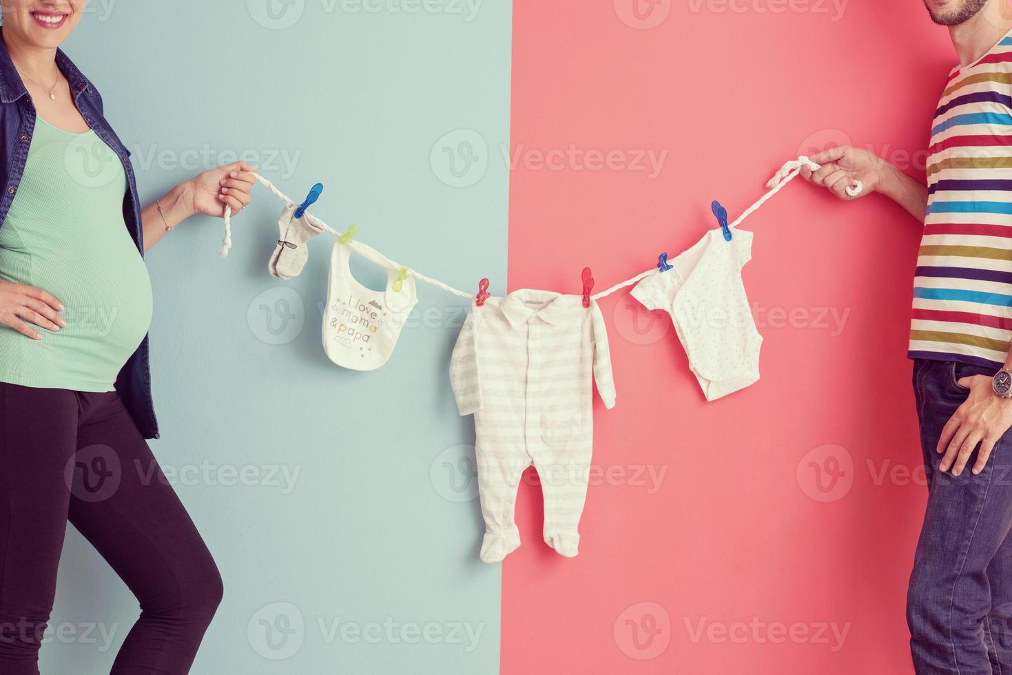 young couple holding baby bodysuits photo