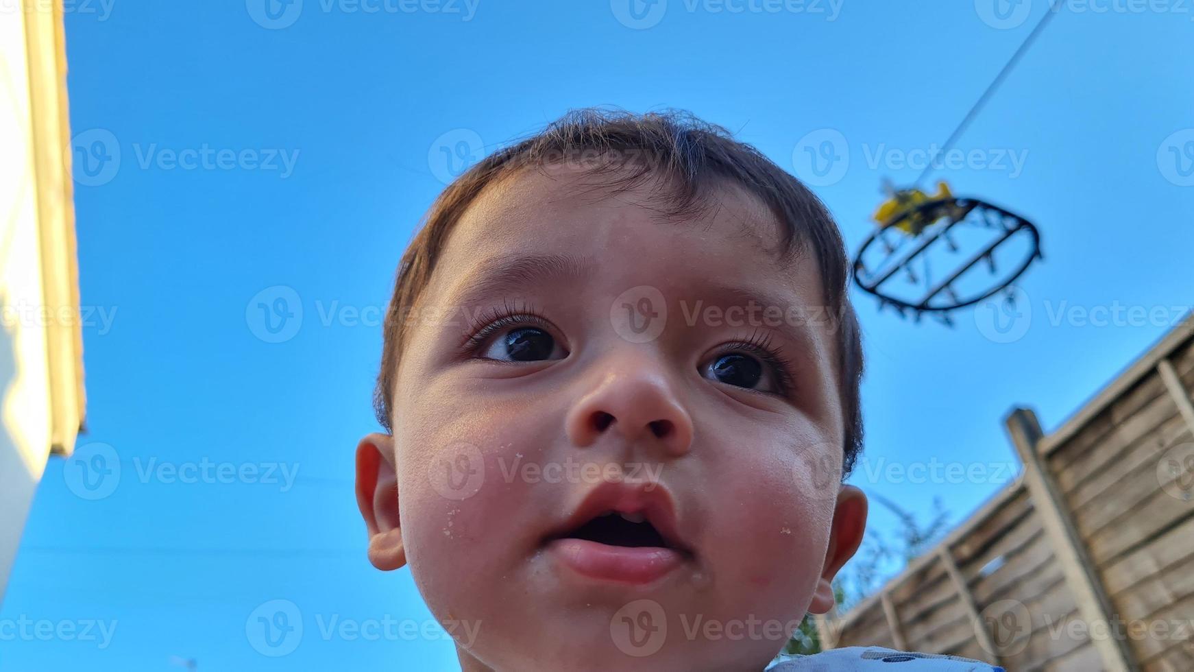 el bebé asiático está posando en el jardín de la casa foto