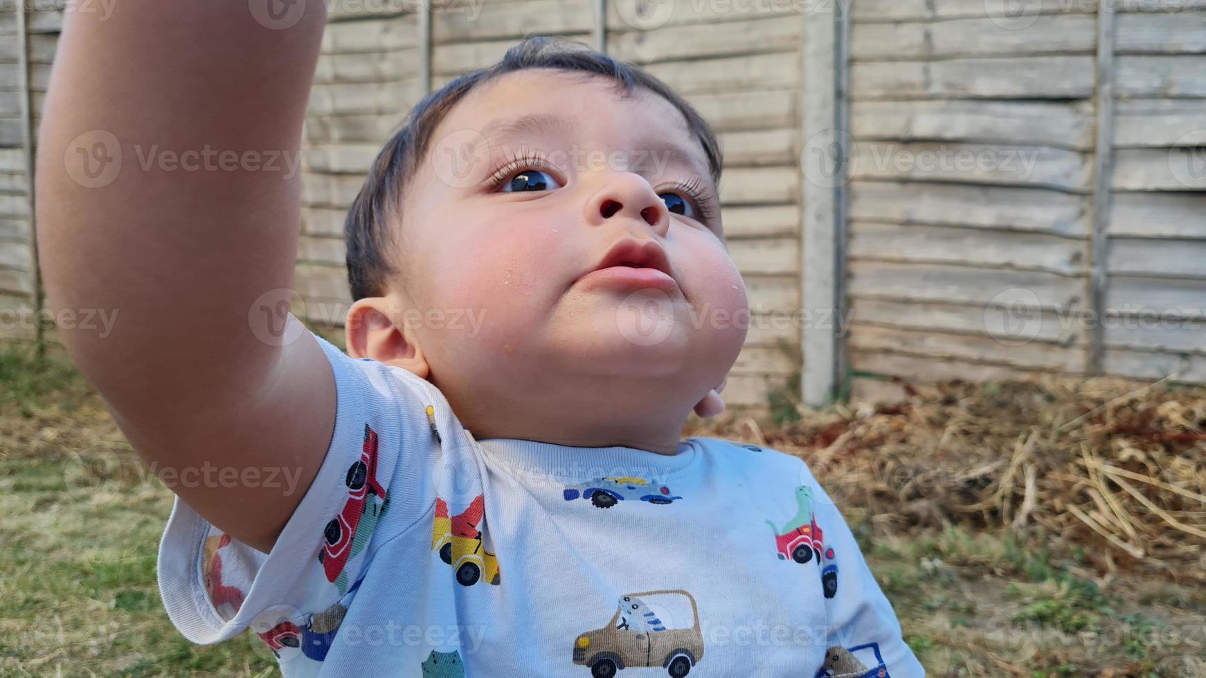 el bebé asiático está posando en el jardín de la casa foto