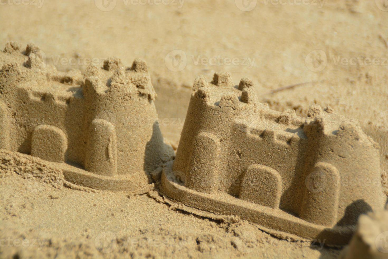 2 castillos de arena de pequeño tamaño en la playa. foto