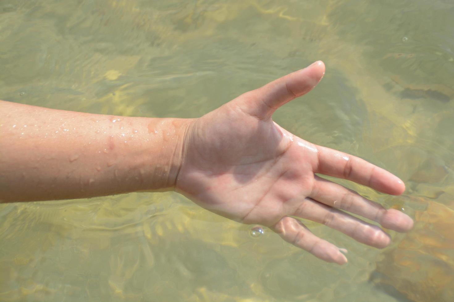 Close-up someone hand play the water in the sea. photo