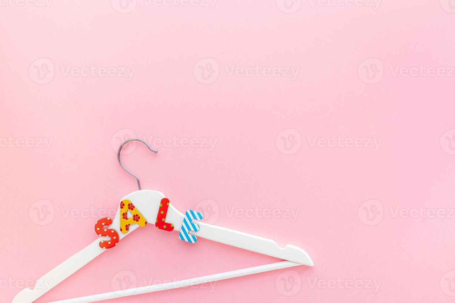 White hangers with sale text on pink background photo