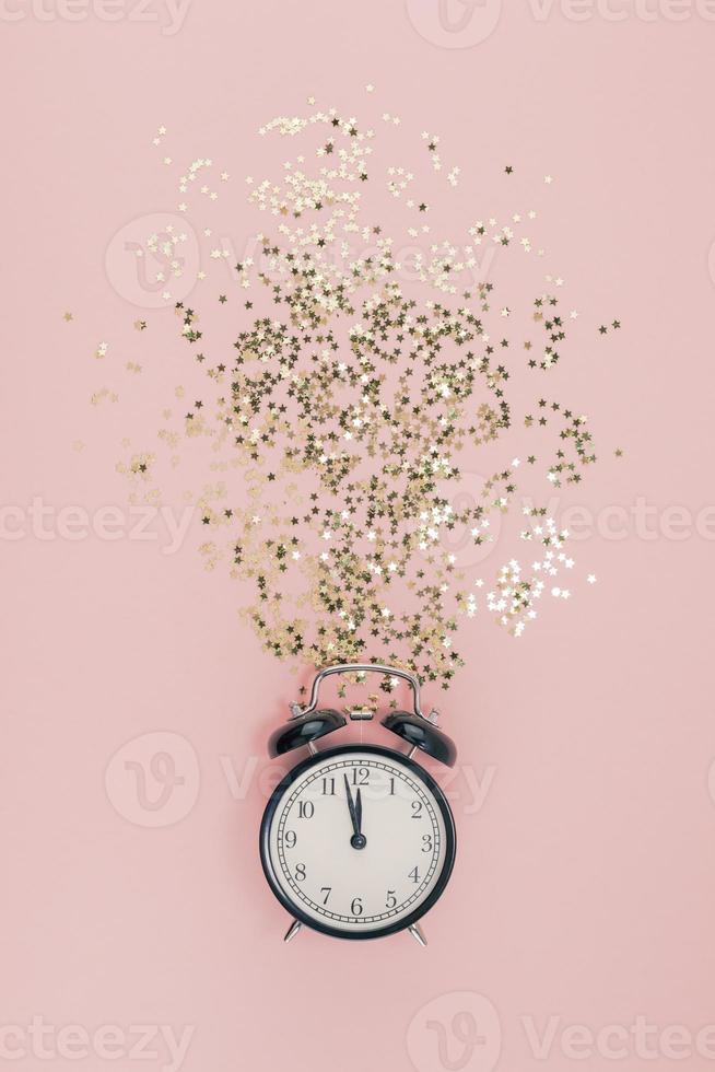 New Year concept. Alarm clock with golden confetti photo