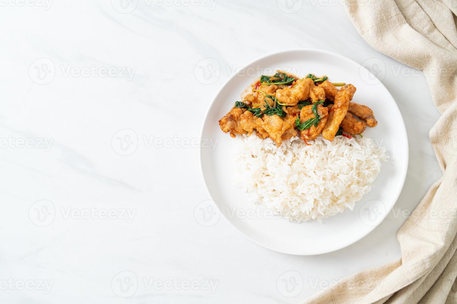 stir-fried fried fish with basil and chili in thai style topped on rice photo