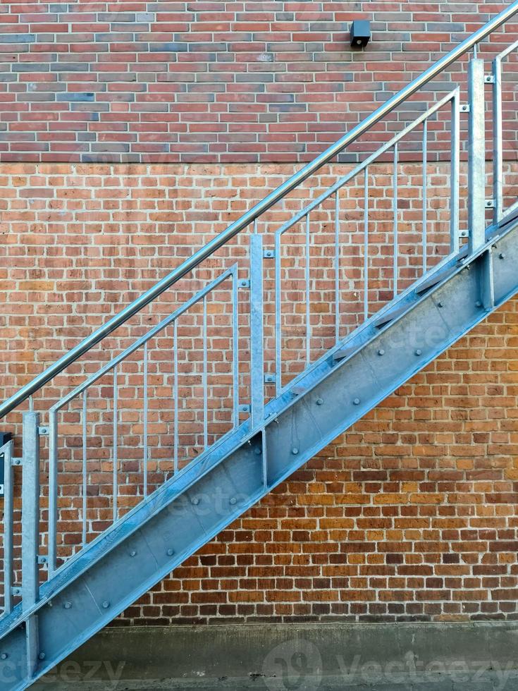 Close up view on metallic stairs in front of a brick wall. photo