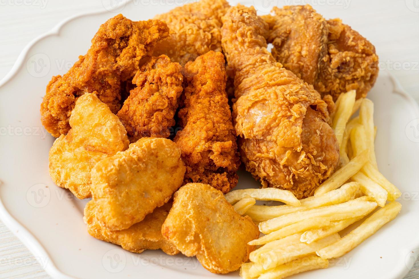 pollo frito con papas fritas y nuggets en un plato foto