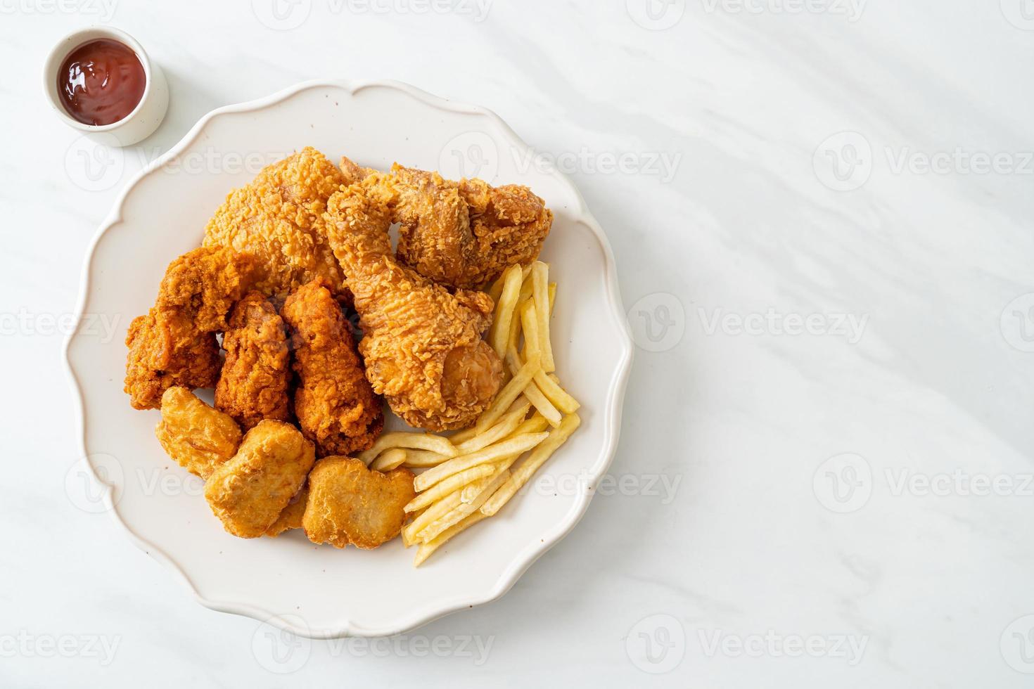 pollo frito con papas fritas y nuggets en un plato foto