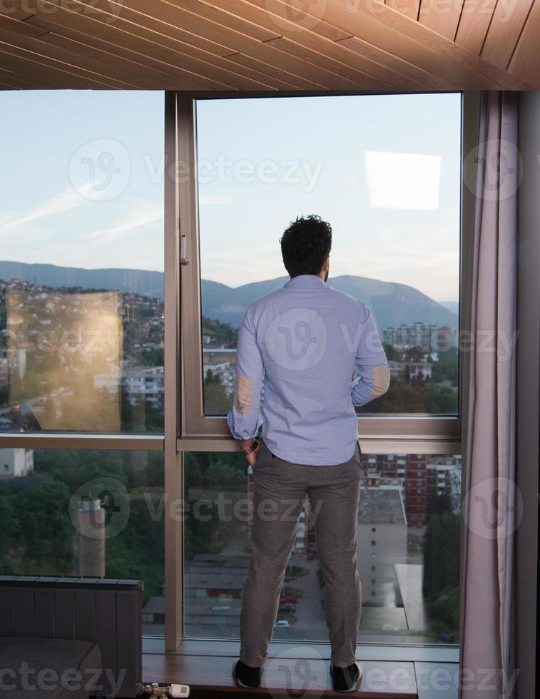 young man enjoying evening coffee by the window photo
