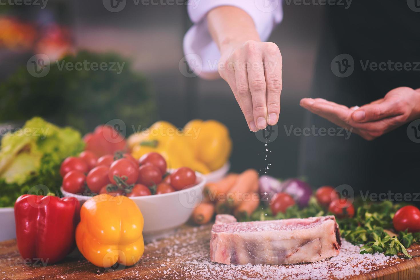 Chef putting salt on juicy slice of raw steak photo