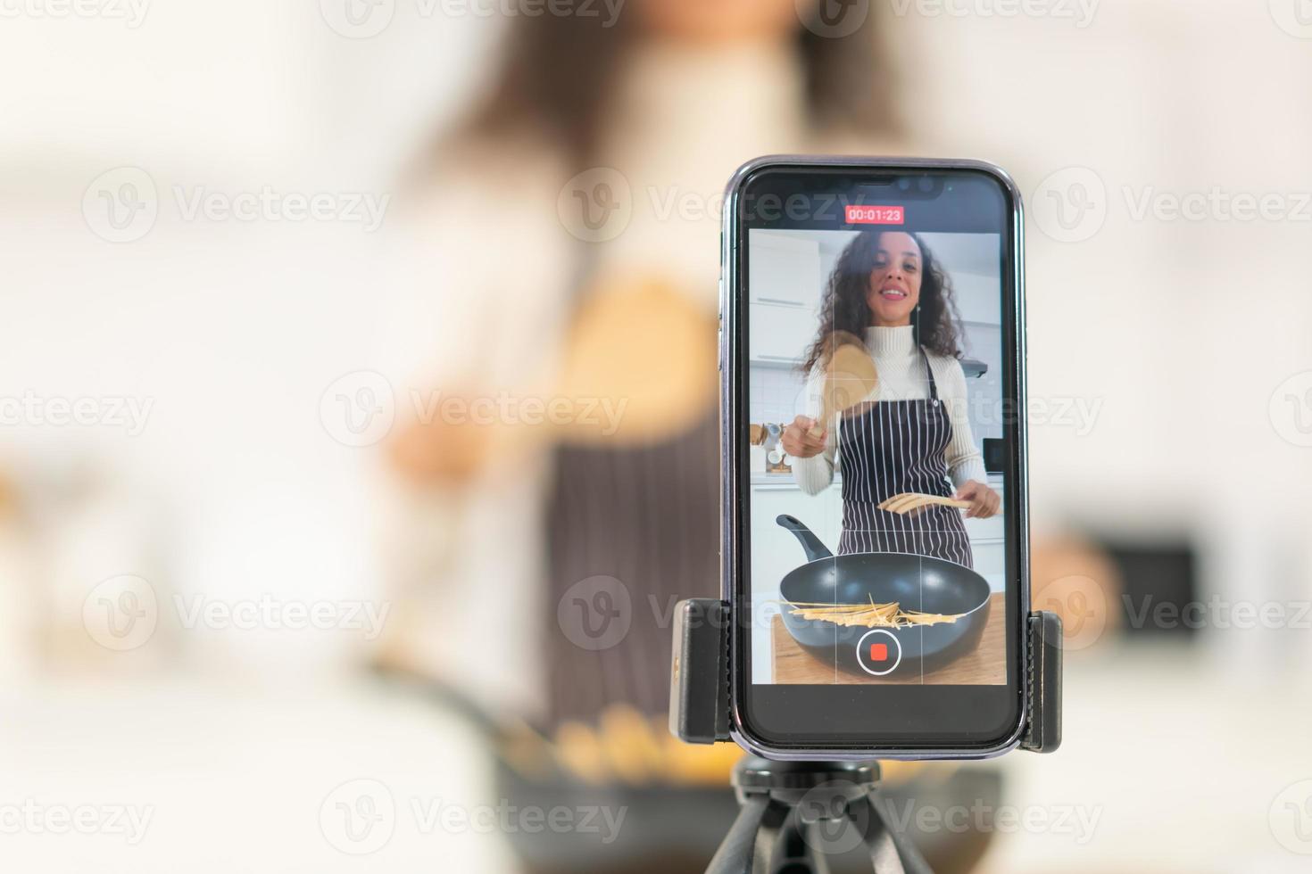 mujer latina grabando video y cocinando en la cocina foto