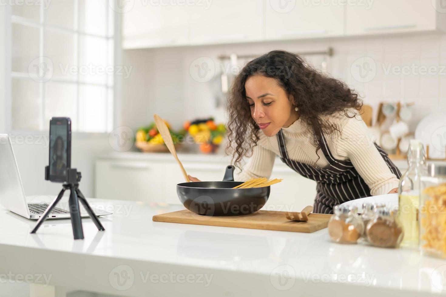 Latin woman shooting video and cooking at the kitchen photo