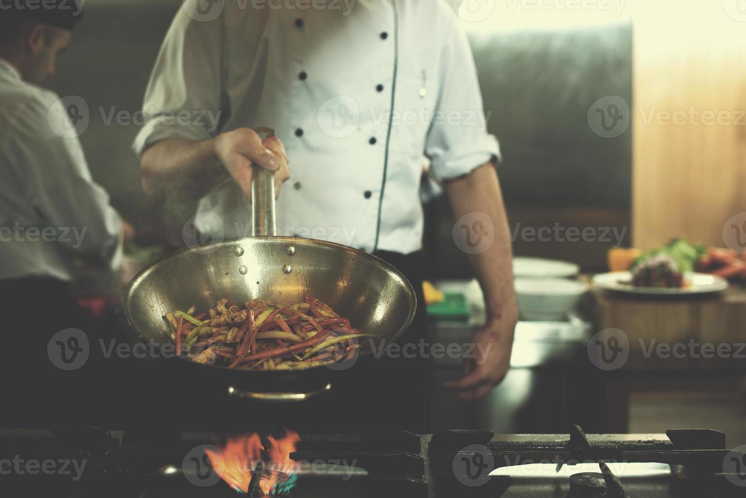 chef volteando verduras en wok foto