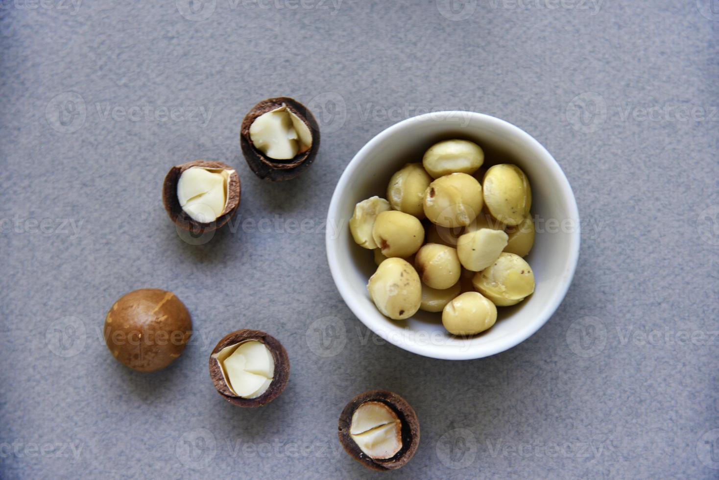 Delicious peeled Macadamia nut in a salad bowl on a gray background. The kernels of a delicious Macadamia nut close-up. photo