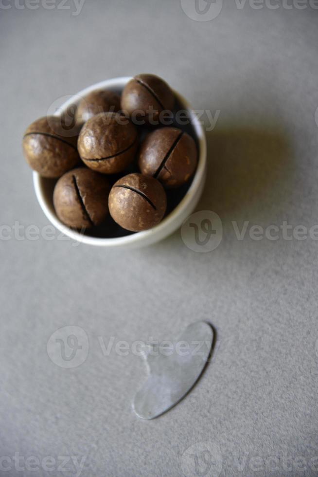 Macadamia nut in a dish with a bottle opener on a gray background. Macadamia nut prepared for use in a vase. Delicious breakfast of nuts. photo