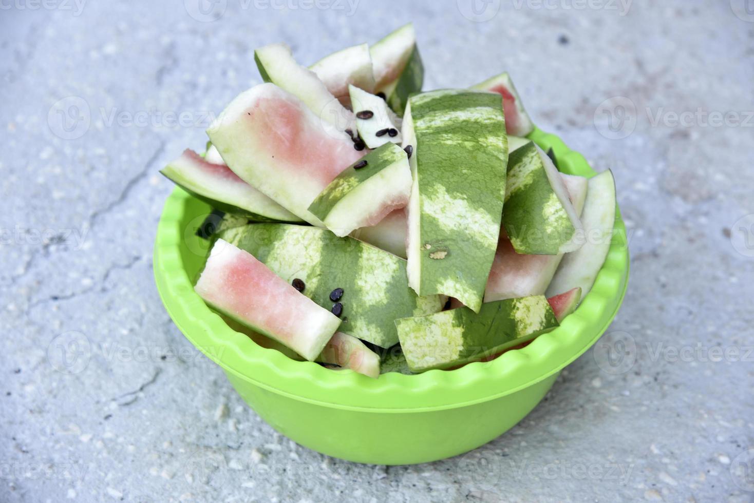 Watermelon rind and leftovers in a green basin. Vegetable garbage in the basket. Leftovers after meals. photo