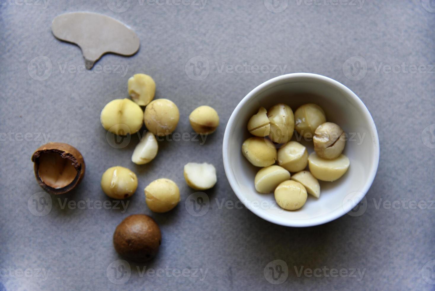 Delicious peeled Macadamia nut in a salad bowl on a gray background. The kernels of a delicious Macadamia nut close-up. photo