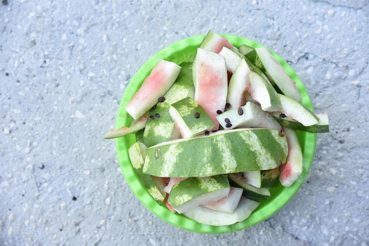 Watermelon rind and leftovers in a green basin. Vegetable garbage in the basket. Leftovers after meals. photo
