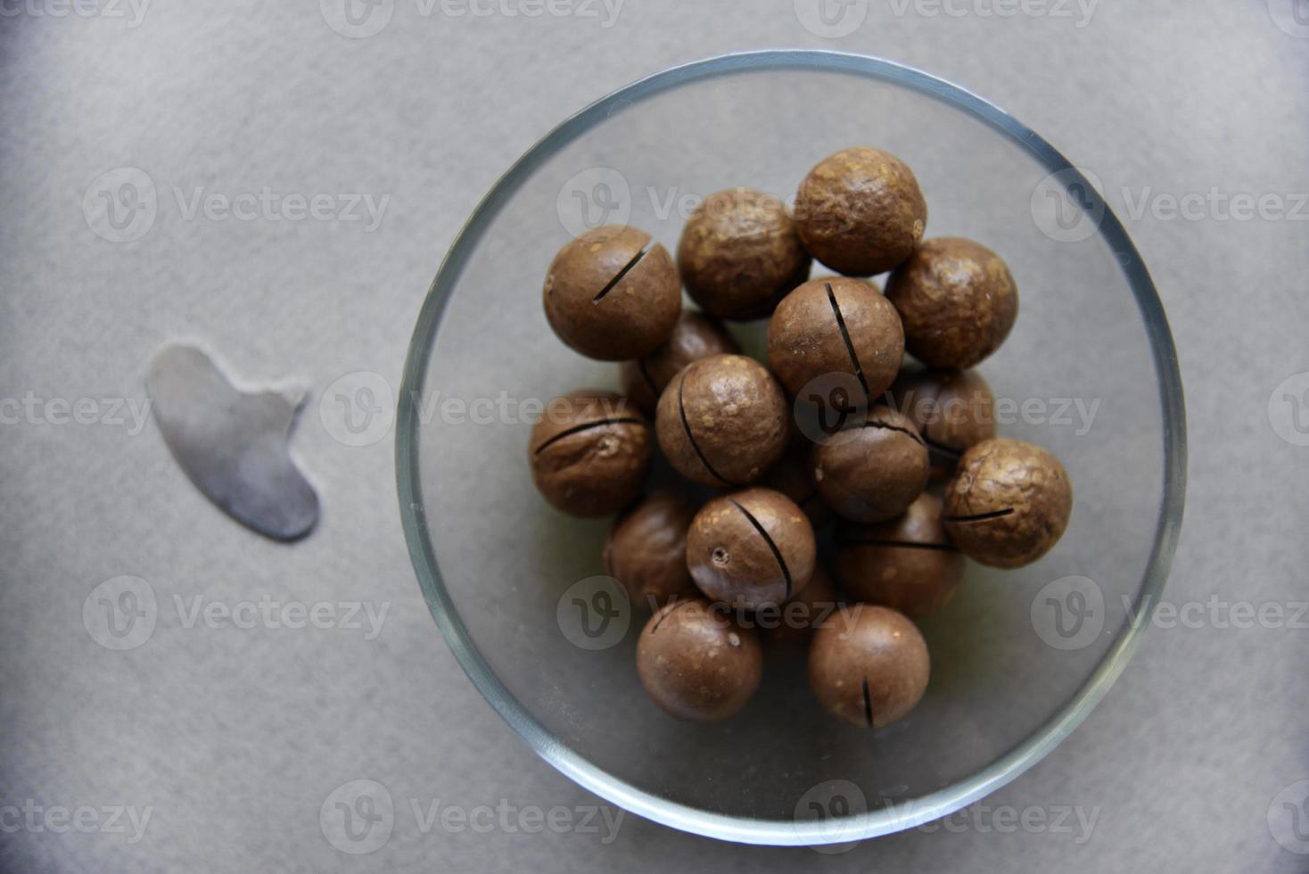 Macadamia nut in a dish with a bottle opener on a gray background. Macadamia nut prepared for use in a vase. Delicious breakfast of nuts. photo