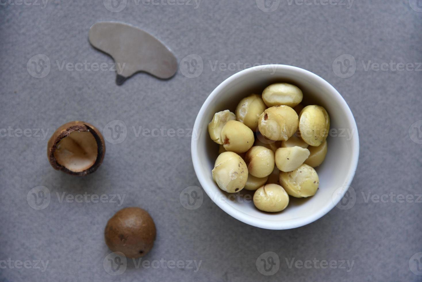 Delicious peeled Macadamia nut in a salad bowl on a gray background. The kernels of a delicious Macadamia nut close-up. photo