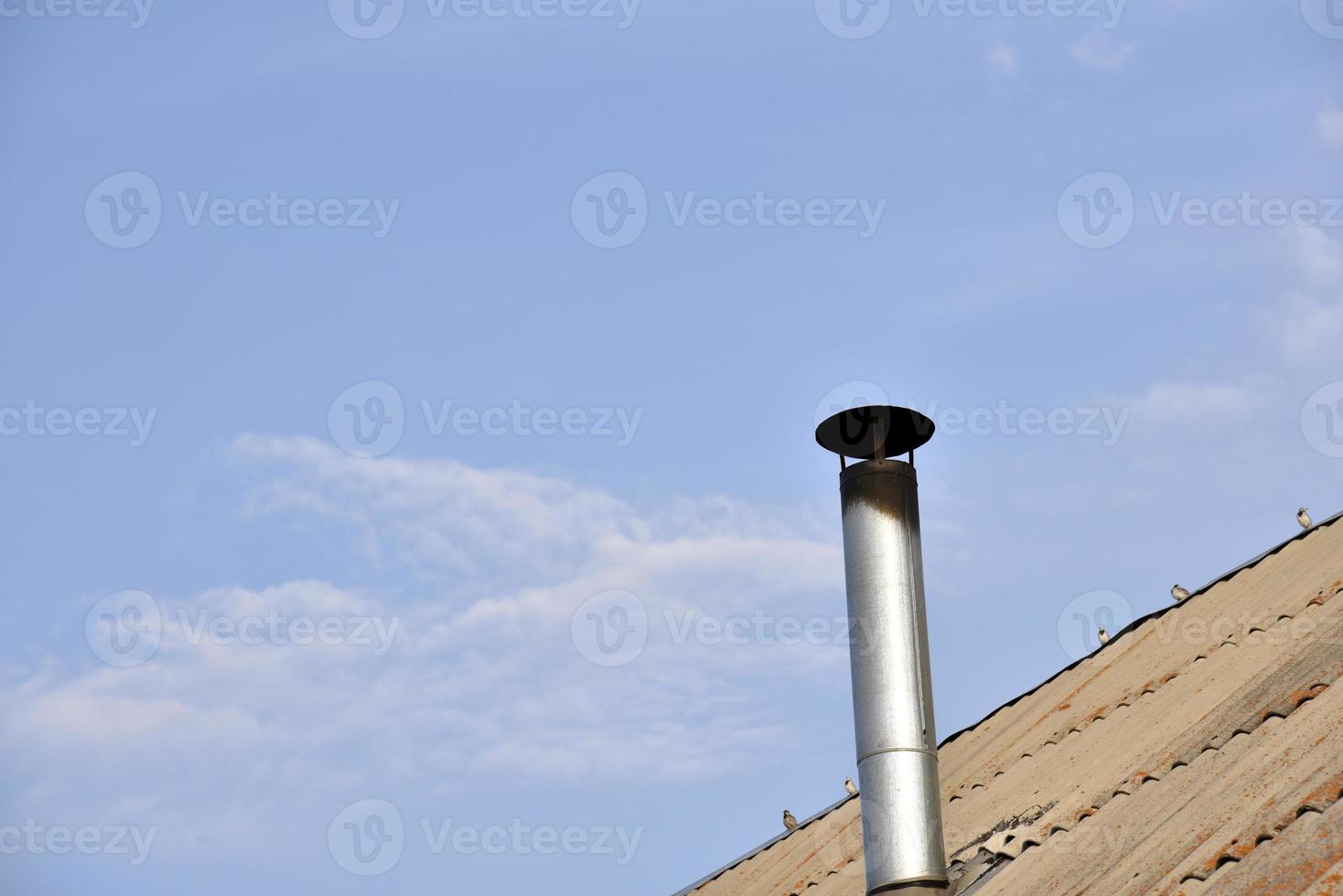 chimenea de metal en el techo de una casa antigua. chimenea chimenea en el fondo de las nubes del cielo. foto