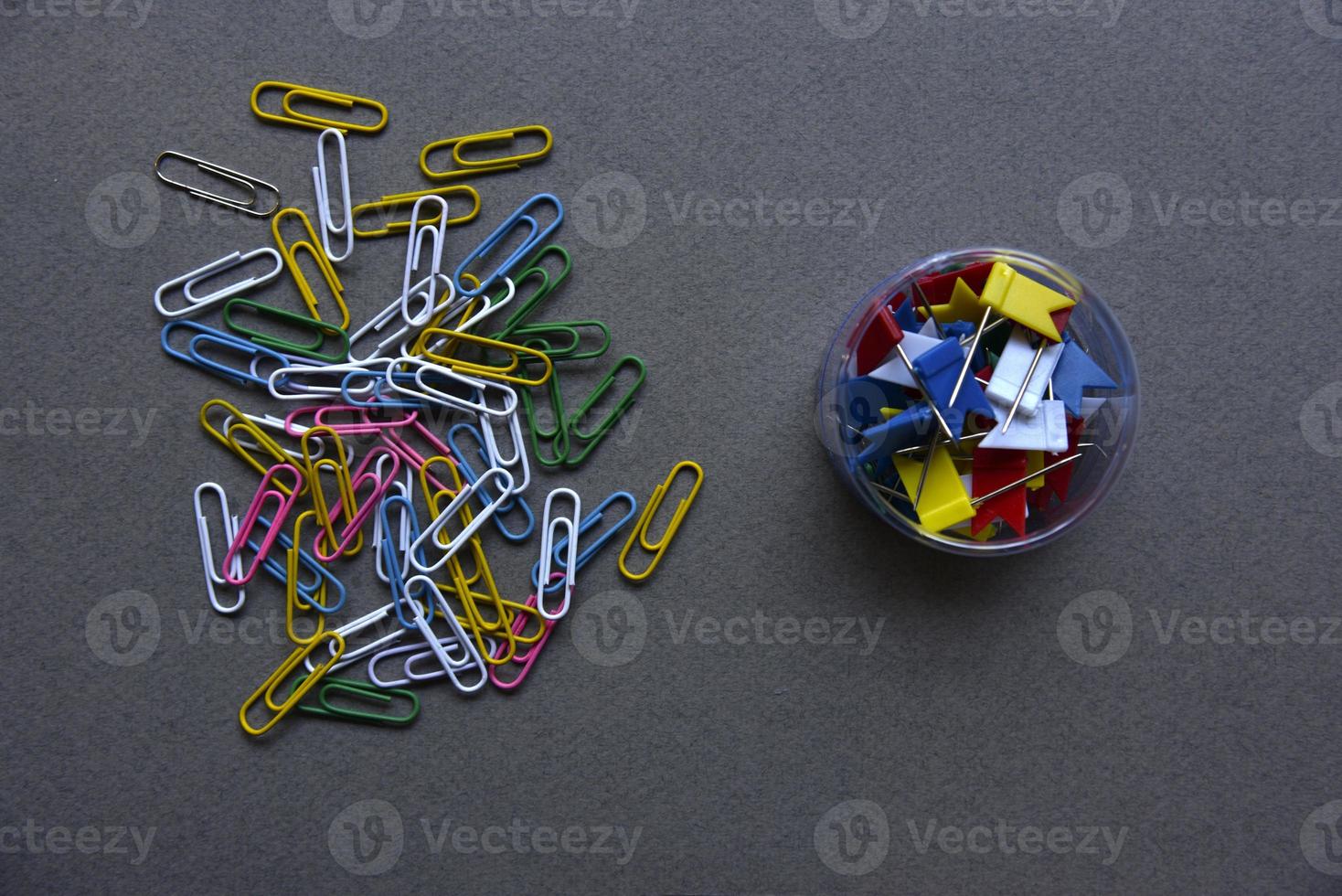 Multicolored paper clips on a gray background and in a jar. Paper clips on a gray background. photo