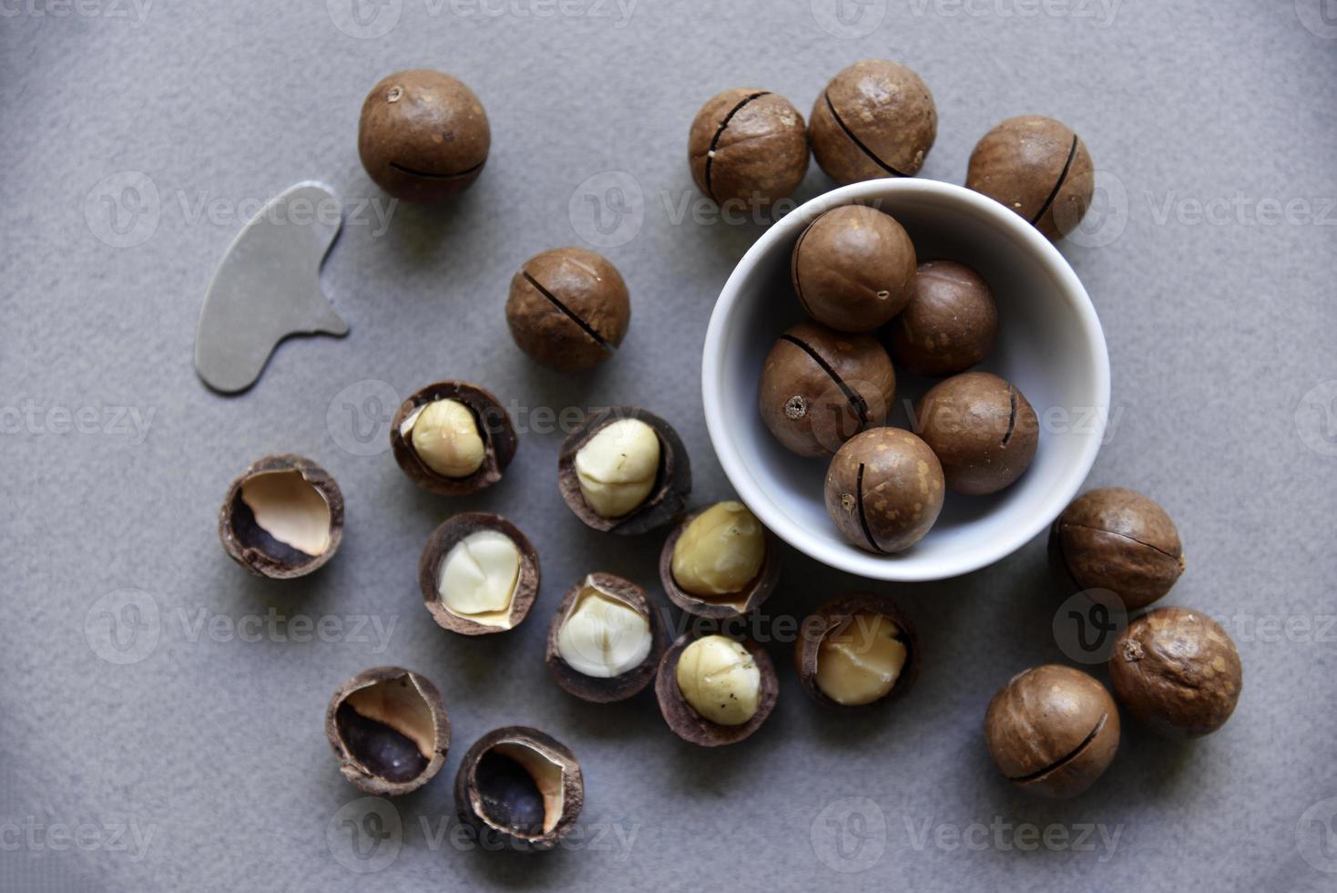 Macadamia nut in a dish with a bottle opener on a gray background. Macadamia nut prepared for use in a vase. Delicious breakfast of nuts. photo